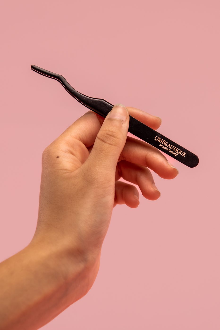 A hand holding branded lash tweezers