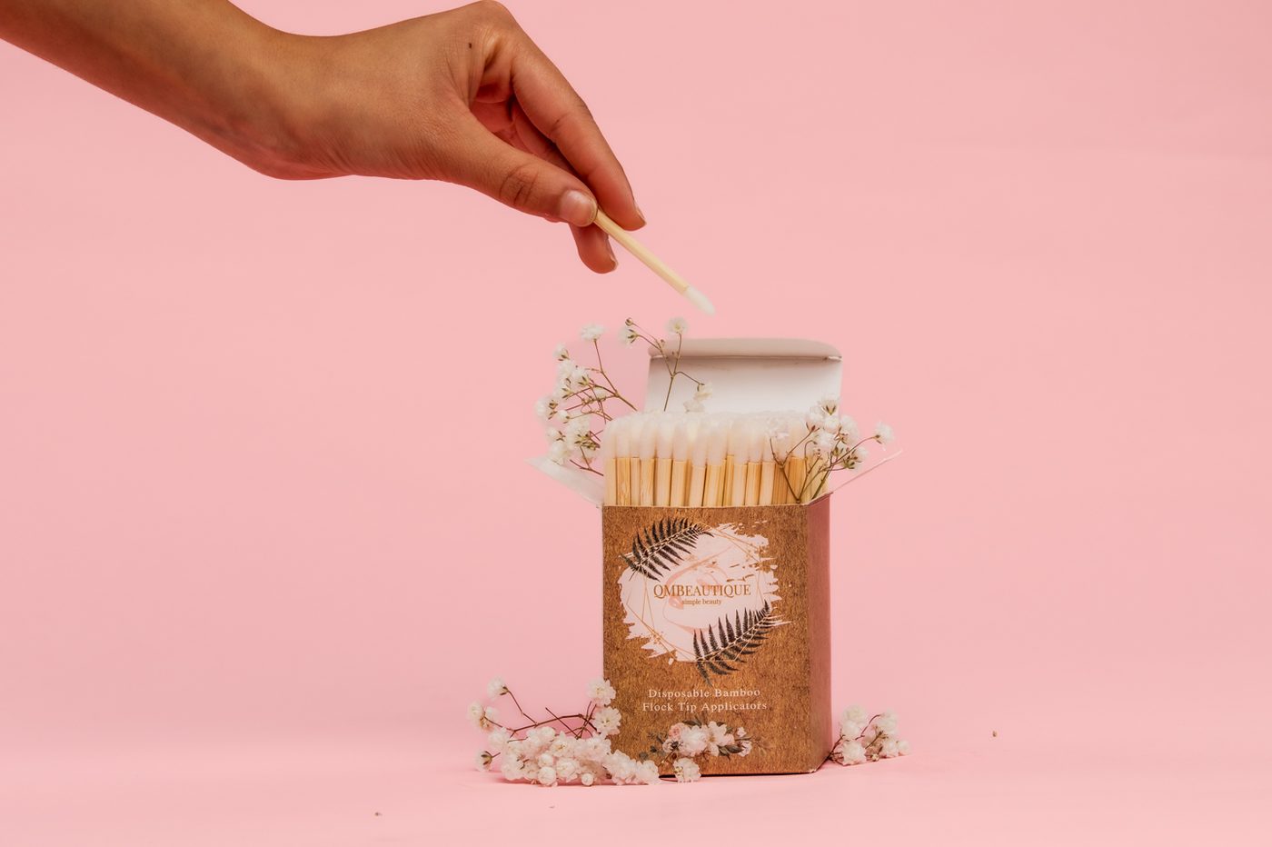 A hand pulling a bamboo applicator from its box